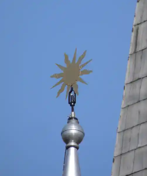 Sun with alternating wavy and straight rays on top of a steeple